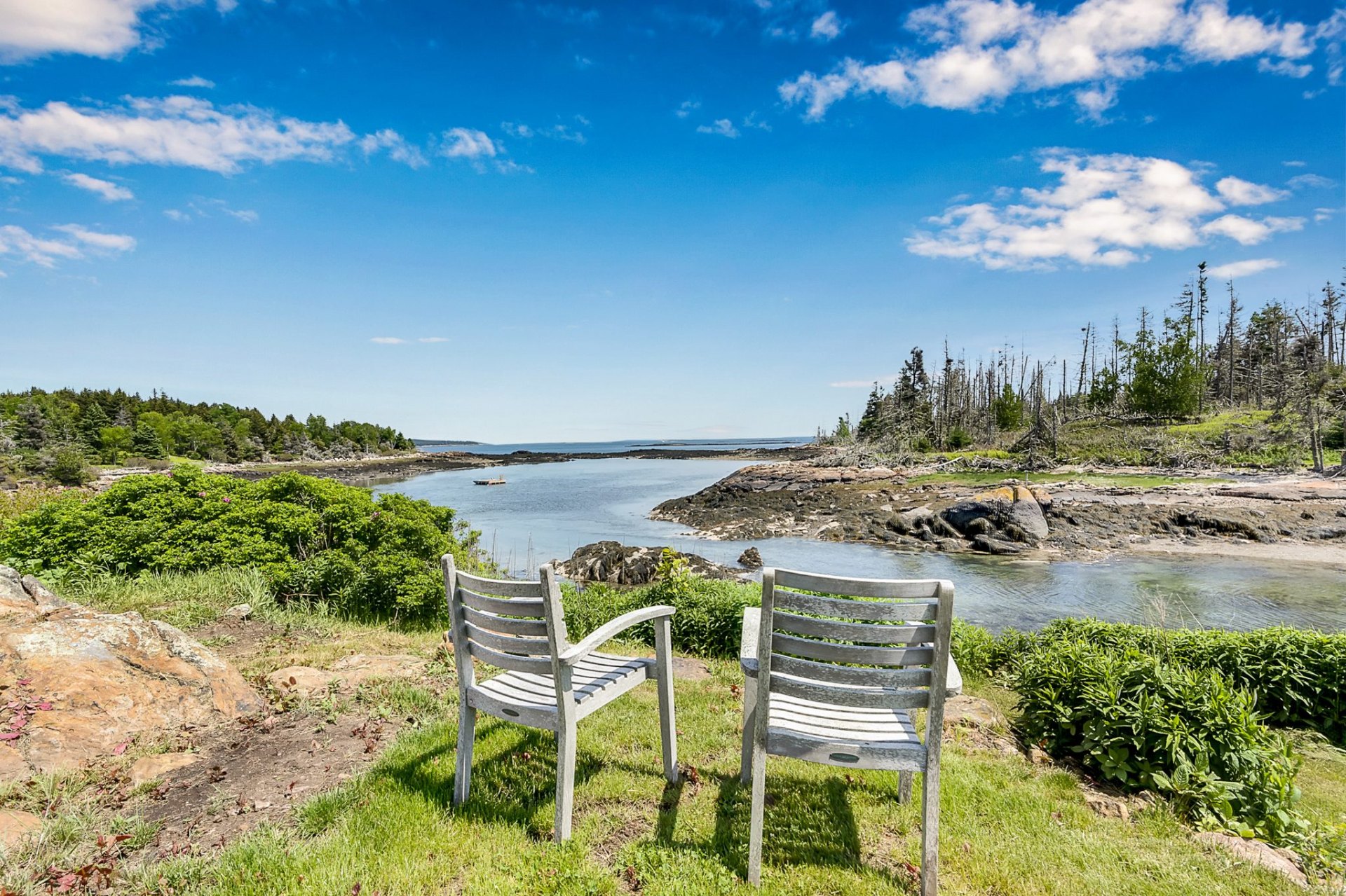 Two weathered Adirondack chairs overlooking the cove from McGee Island